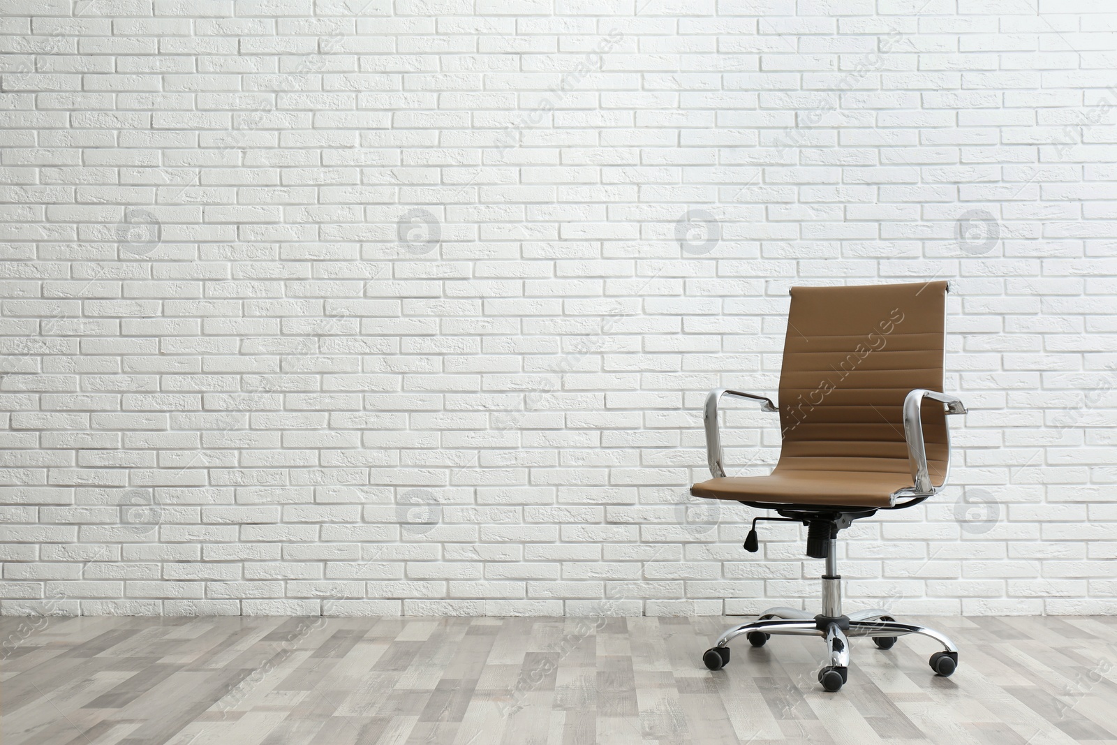 Photo of Comfortable office chair near white brick wall indoors. Space for text