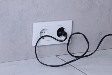 Power sockets and electric plug on grey wall