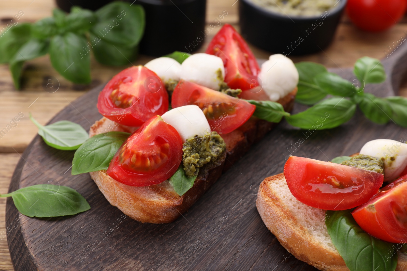 Photo of Delicious Caprese sandwiches with mozzarella, tomatoes, basil and pesto sauce on wooden table, closeup