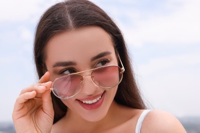 Beautiful smiling woman wearing stylish sunglasses outdoors