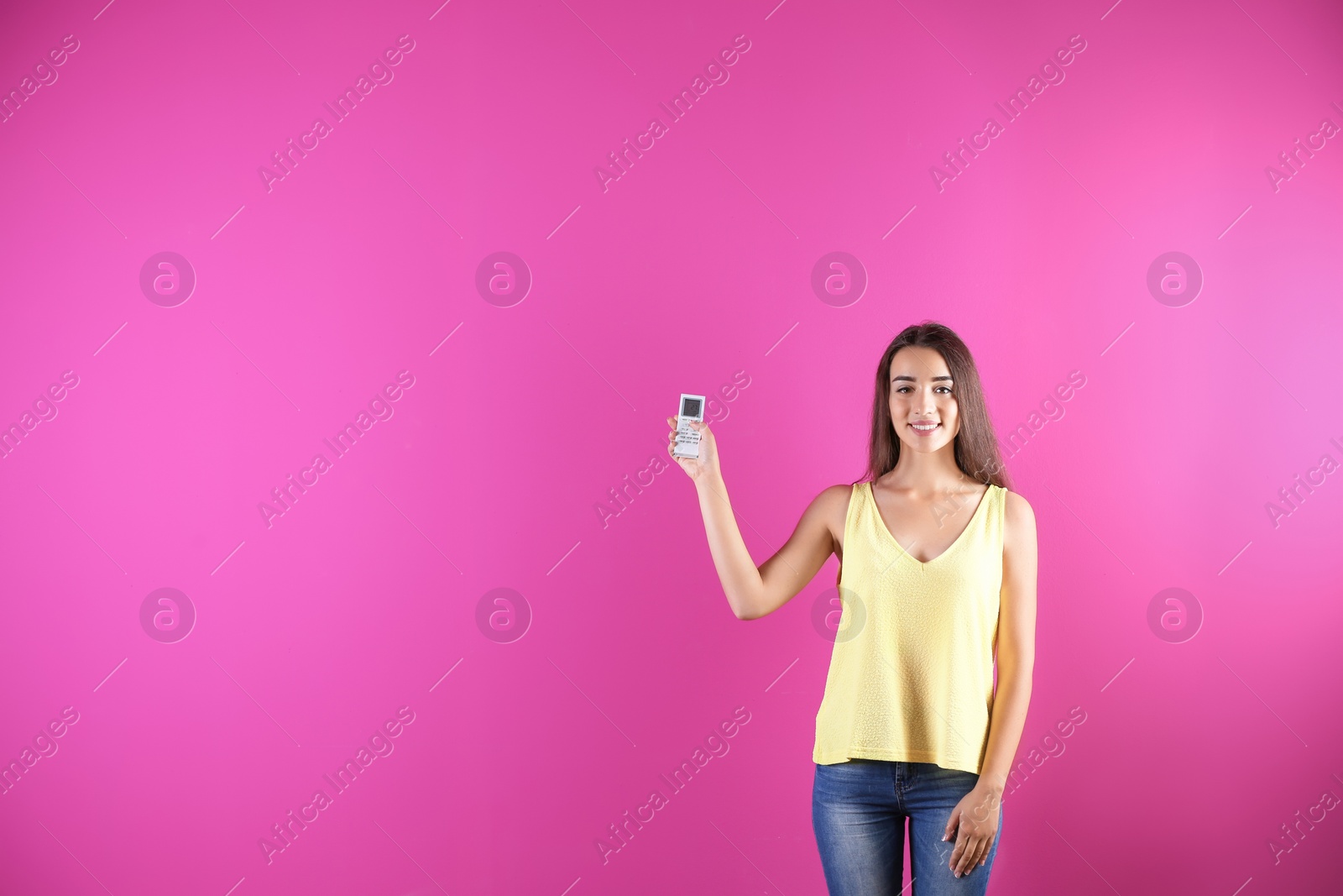 Photo of Young woman switching on air conditioner on color background