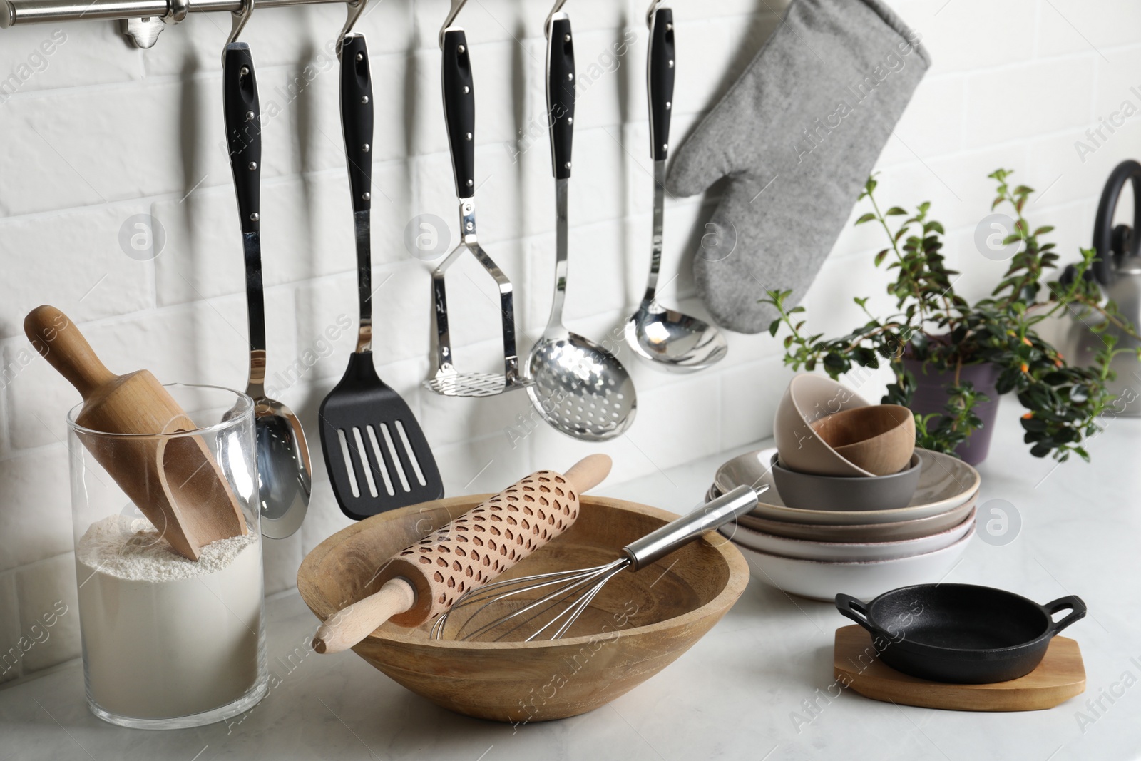 Photo of Different cooking utensils and plant on countertop in kitchen