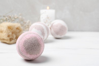 Photo of Bath bombs, loofah sponge and candle on white table, space for text