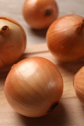 Photo of Many ripe onions on wooden table, closeup