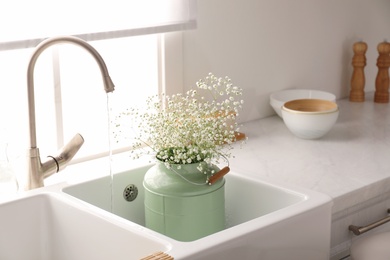 Photo of Bouquet of gypsophila flowers in sink. Kitchen interior design