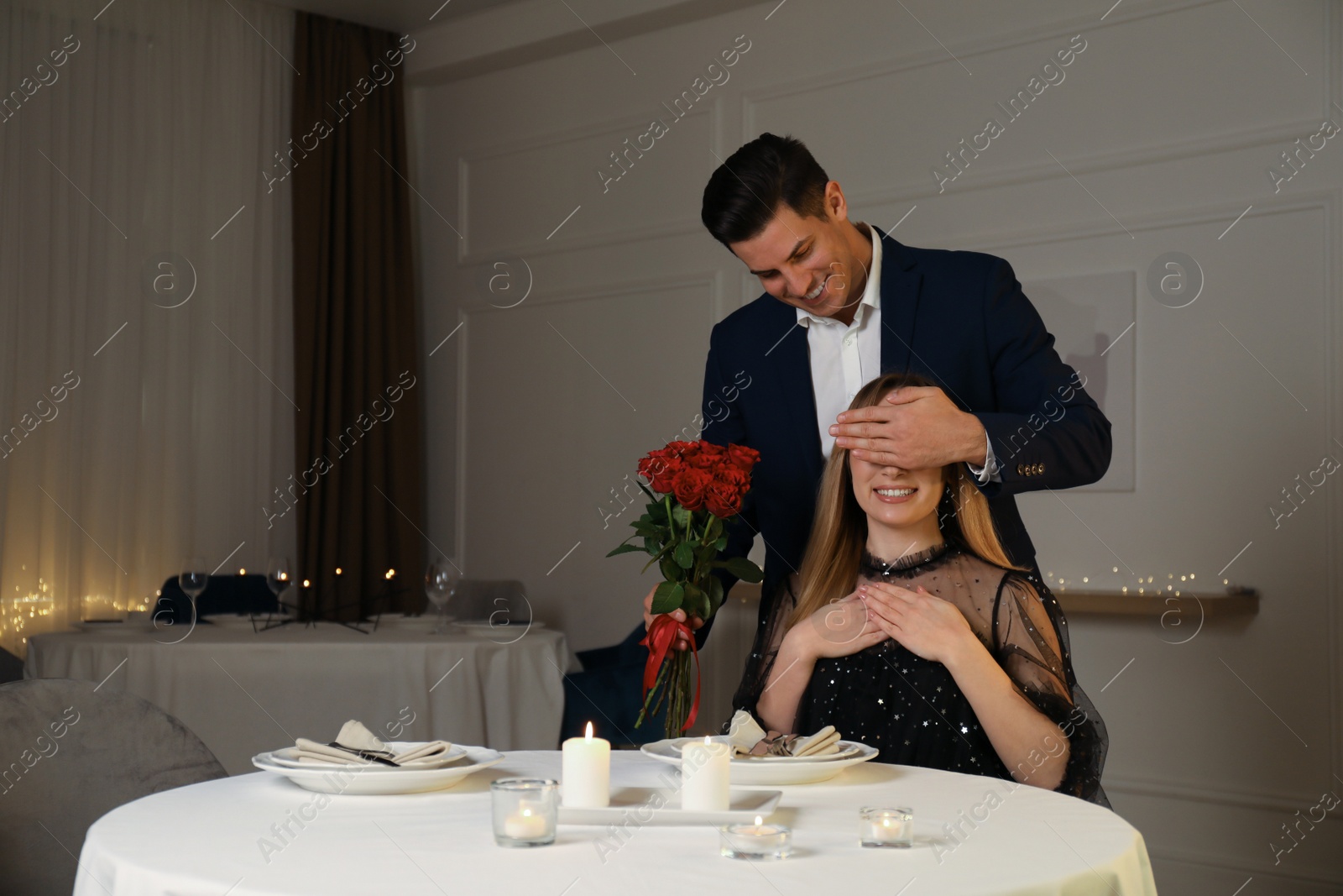Photo of Man presenting roses to his beloved woman in restaurant at romantic dinner
