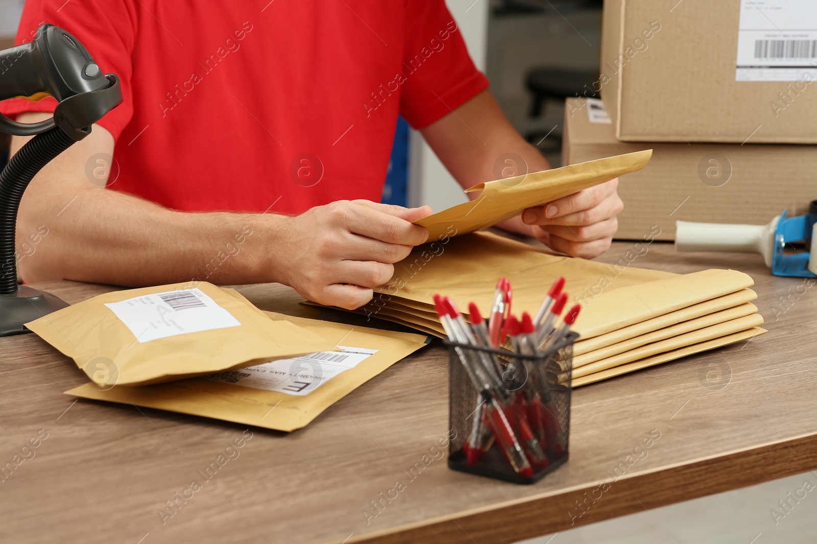 Photo of Post office worker with adhesive paper bags at counter indoors, closeup