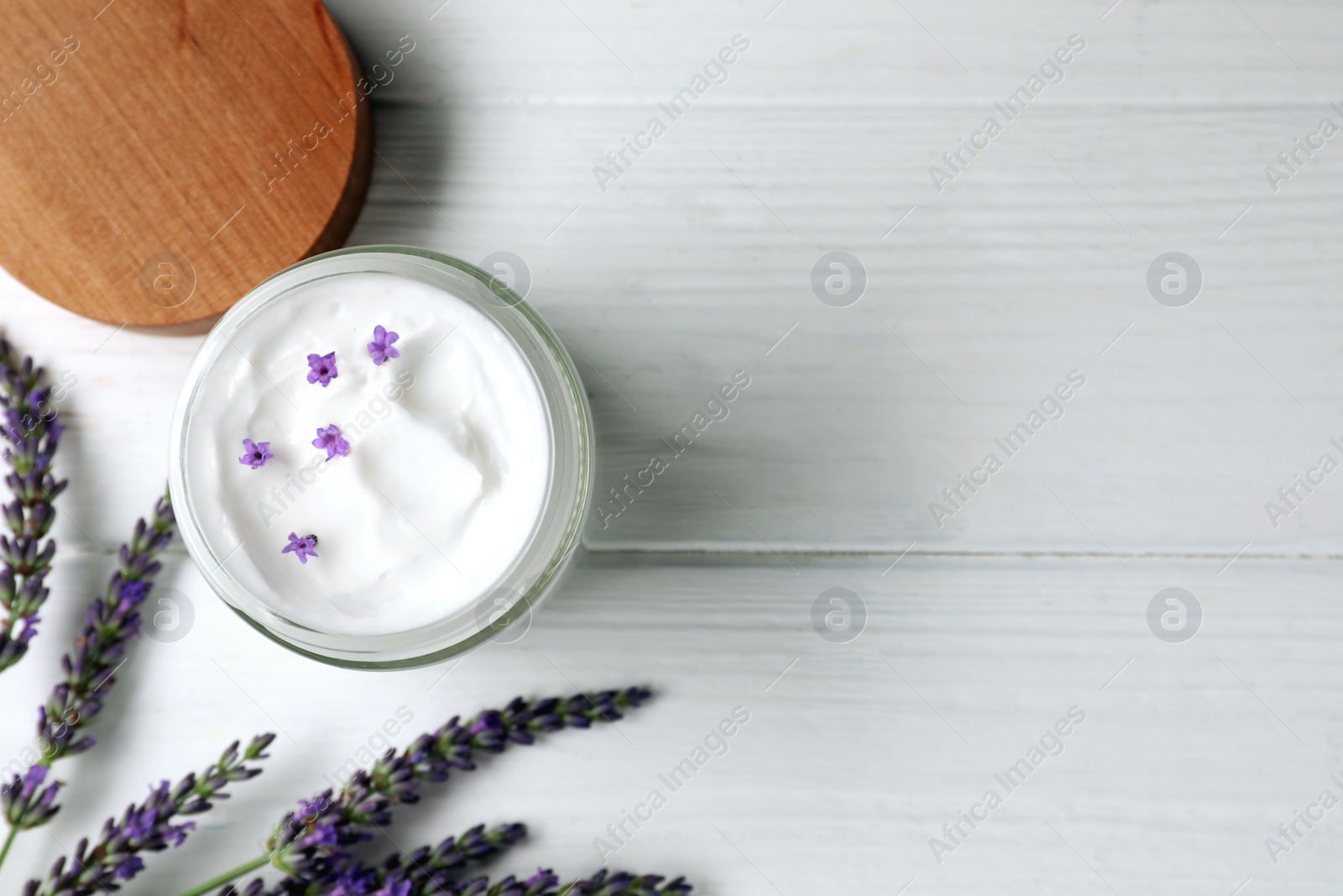 Photo of Jar of face cream and beautiful lavender on white wooden table, flat lay. Space for text