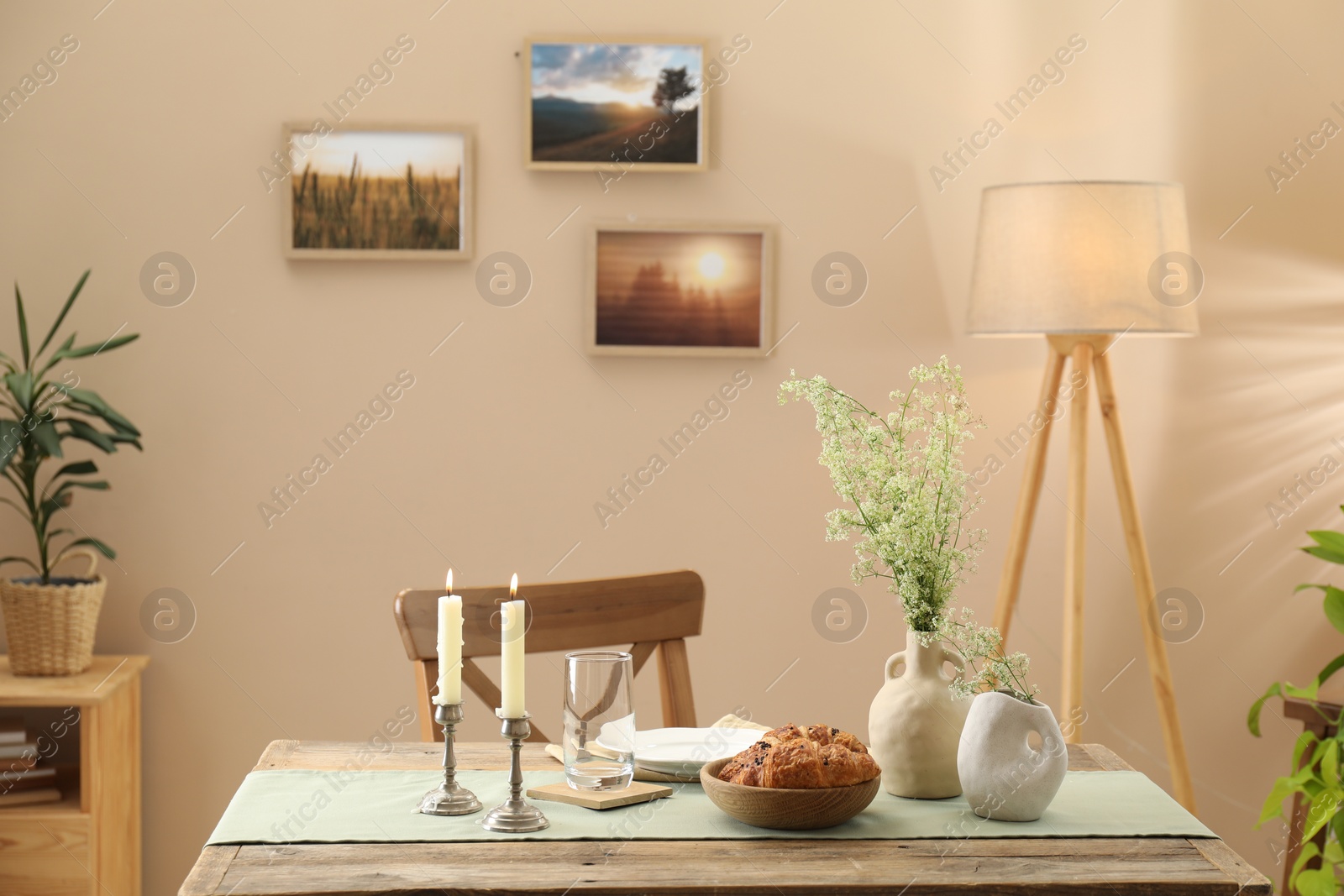 Photo of Clean tableware, candlesticks, flowers and fresh pastries on table in stylish dining room