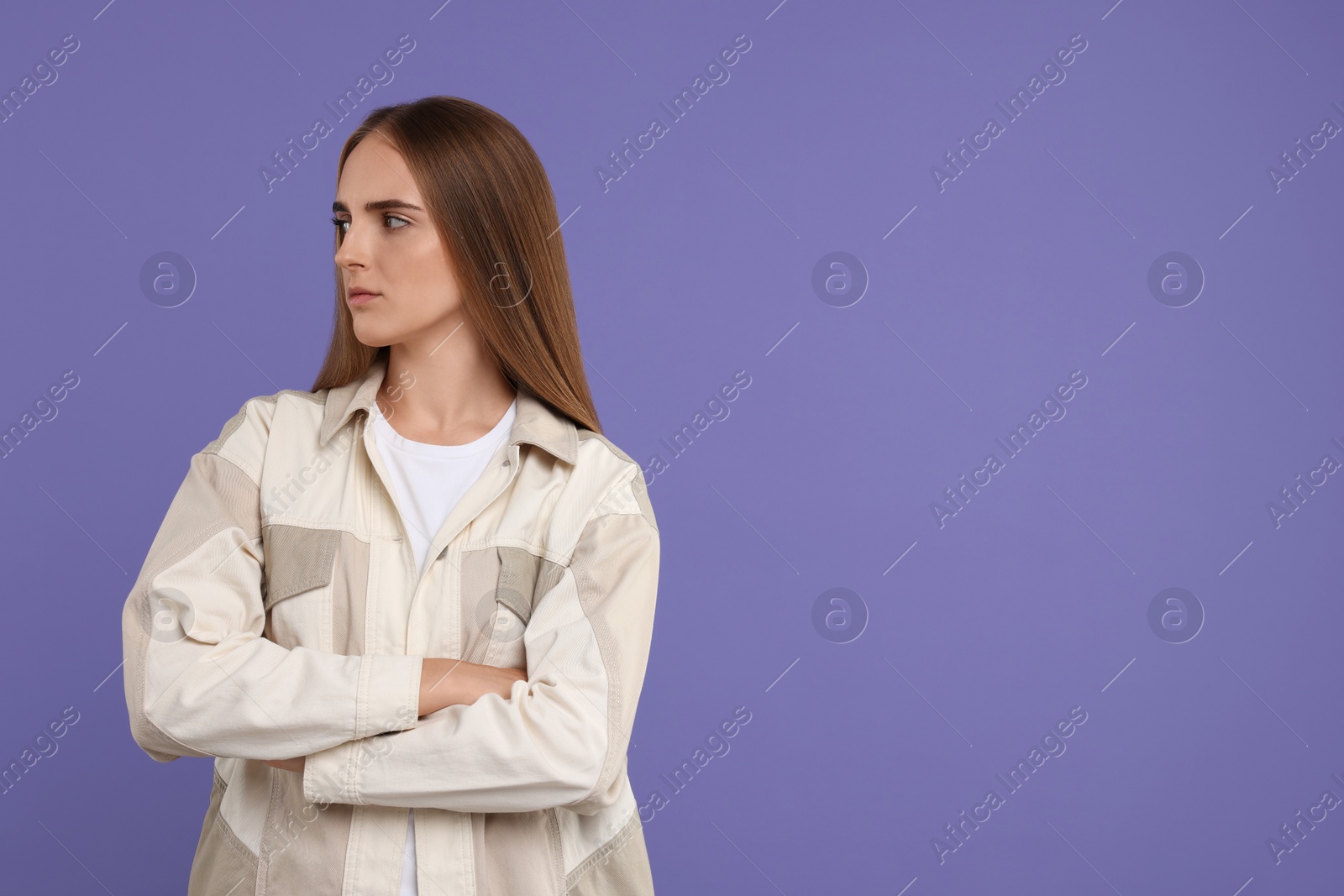 Photo of Resentful woman with crossed arms on violet background, space for text