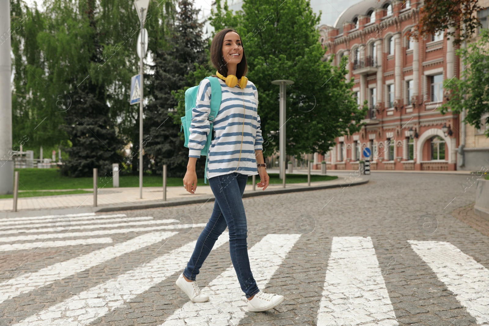 Photo of Young woman crossing street. Traffic rules and regulations