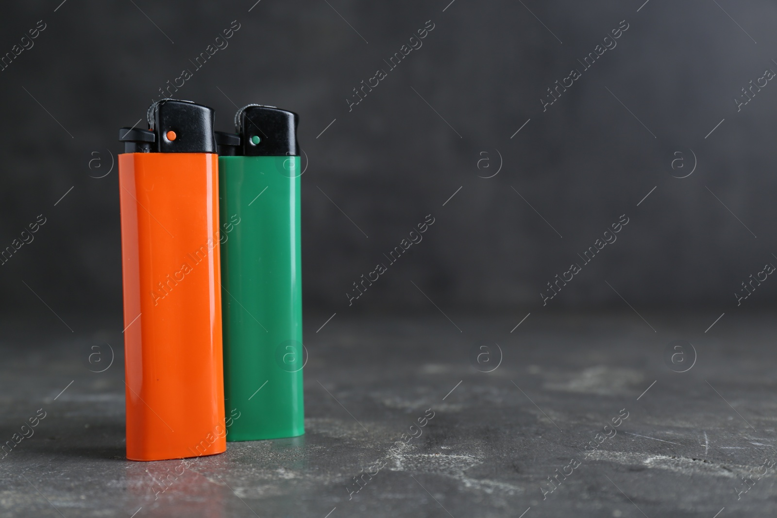 Photo of Stylish small pocket lighters on grey table, space for text