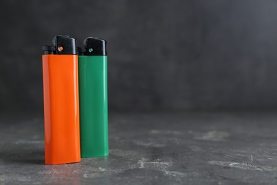 Photo of Stylish small pocket lighters on grey table, space for text