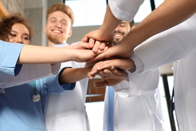 Photo of Team of medical workers holding hands together in hispital, closeup. Unity concept