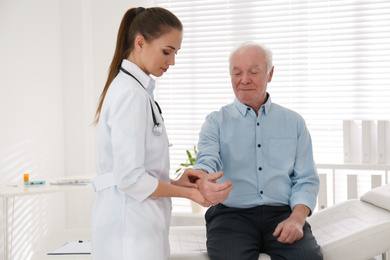 Photo of Doctor checking pulse of senior patient in office