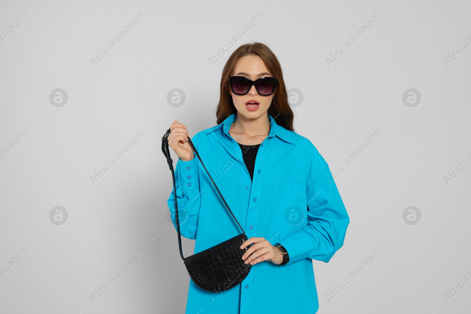 Photo of Emotional young woman in fashionable outfit with stylish bag on white background