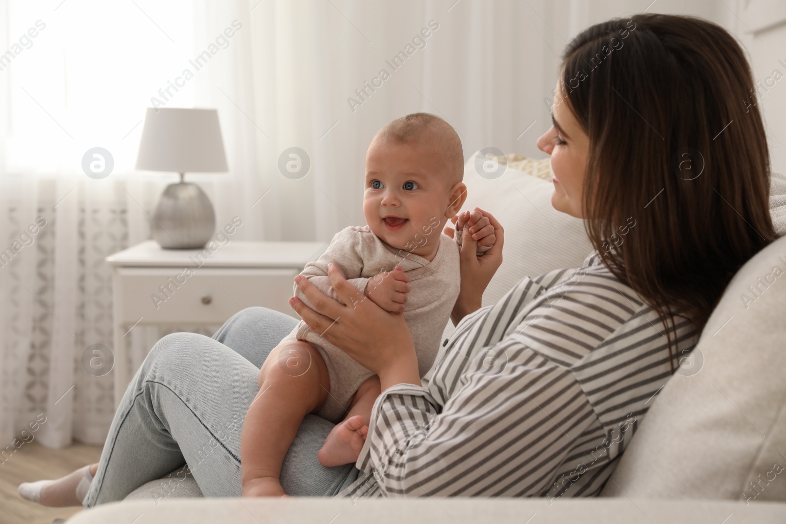 Photo of Young woman with her little baby on sofa at home