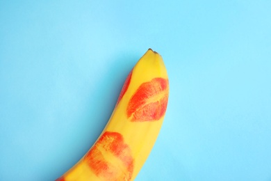 Photo of Top view of fresh banana with red lipstick marks on blue background. Oral sex concept