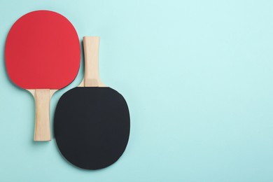 Photo of Ping pong rackets on turquoise background, flat lay. Space for text