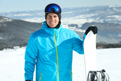 Happy man with snowboard in mountains. Winter vacation