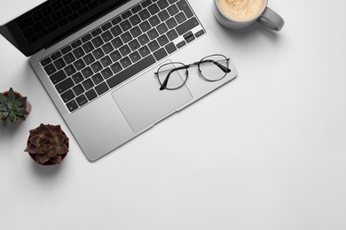 Modern laptop, houseplants, glasses and cup of coffee on white table, flat lay. Space for text
