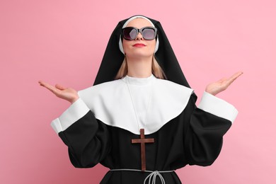 Photo of Woman in nun habit and sunglasses against pink background