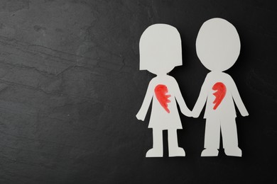 Human paper figures with parted heart and space for text on black stone background, flat lay. Composition symbolizing problems in relationship