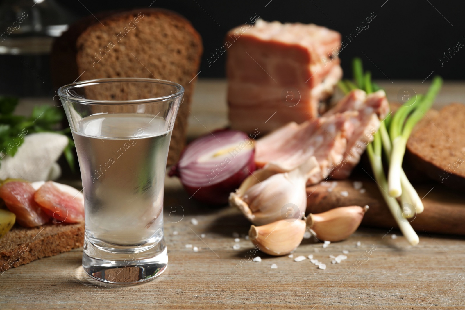 Photo of Cold Russian vodka with snacks on wooden table, closeup