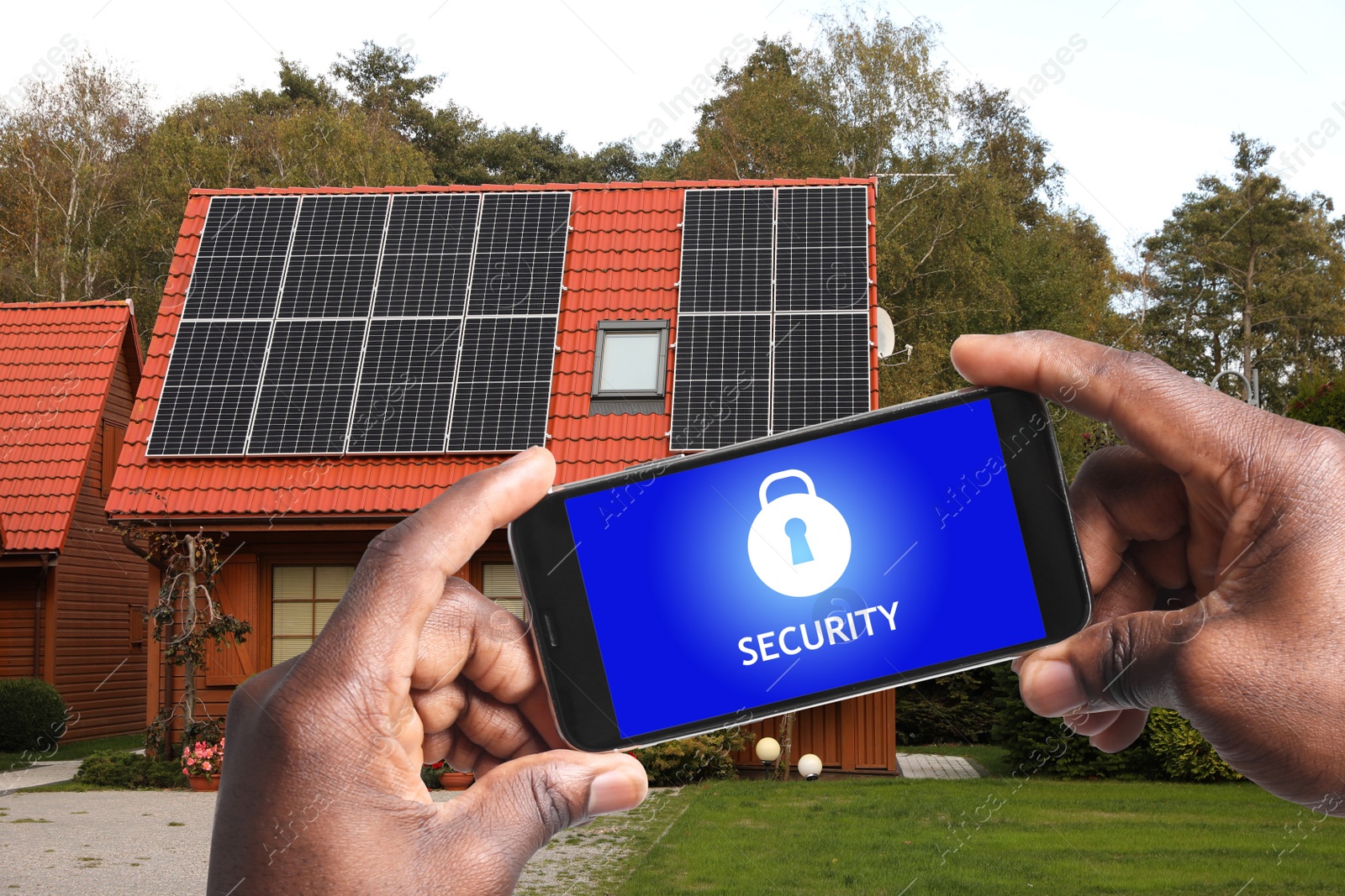 Image of Home security system. African American man with smartphone near his house outdoors, closeup