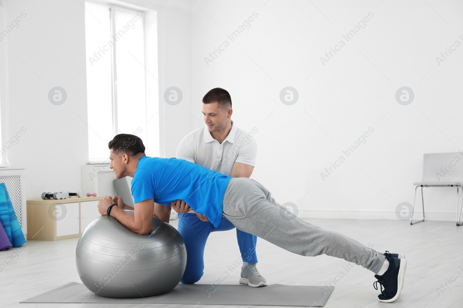 Photo of Professional physiotherapist working with male patient in rehabilitation center