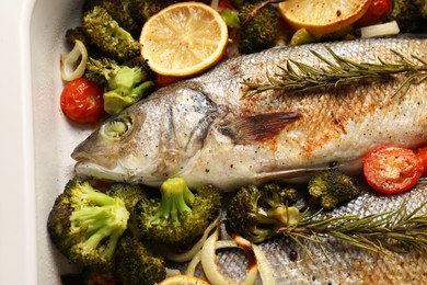 Photo of Delicious fish with vegetables and lemon in baking dish, closeup