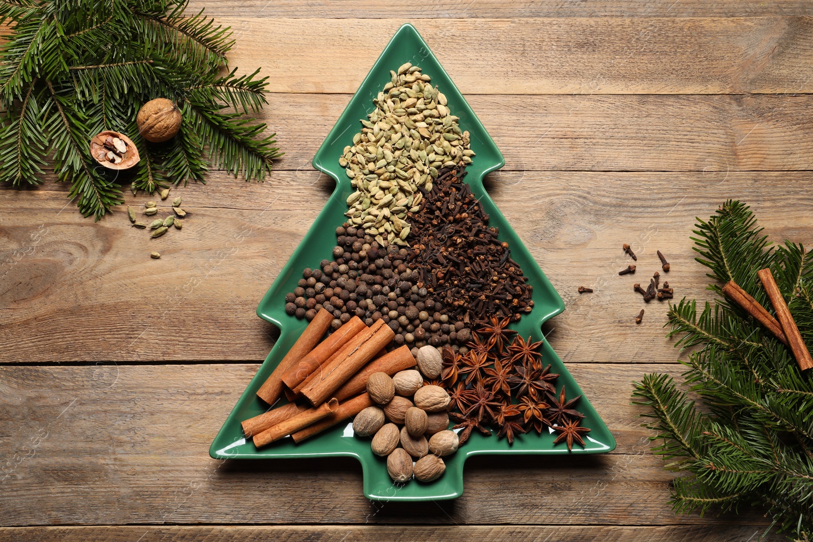 Photo of Different spices, nuts and fir branches on wooden table, flat lay