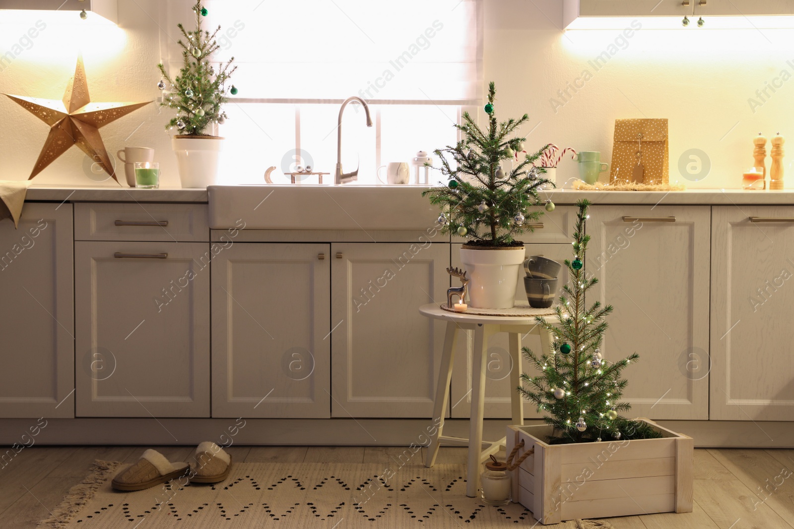 Photo of Small Christmas trees and festive decor in kitchen