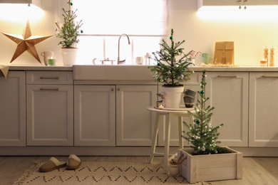 Photo of Small Christmas trees and festive decor in kitchen