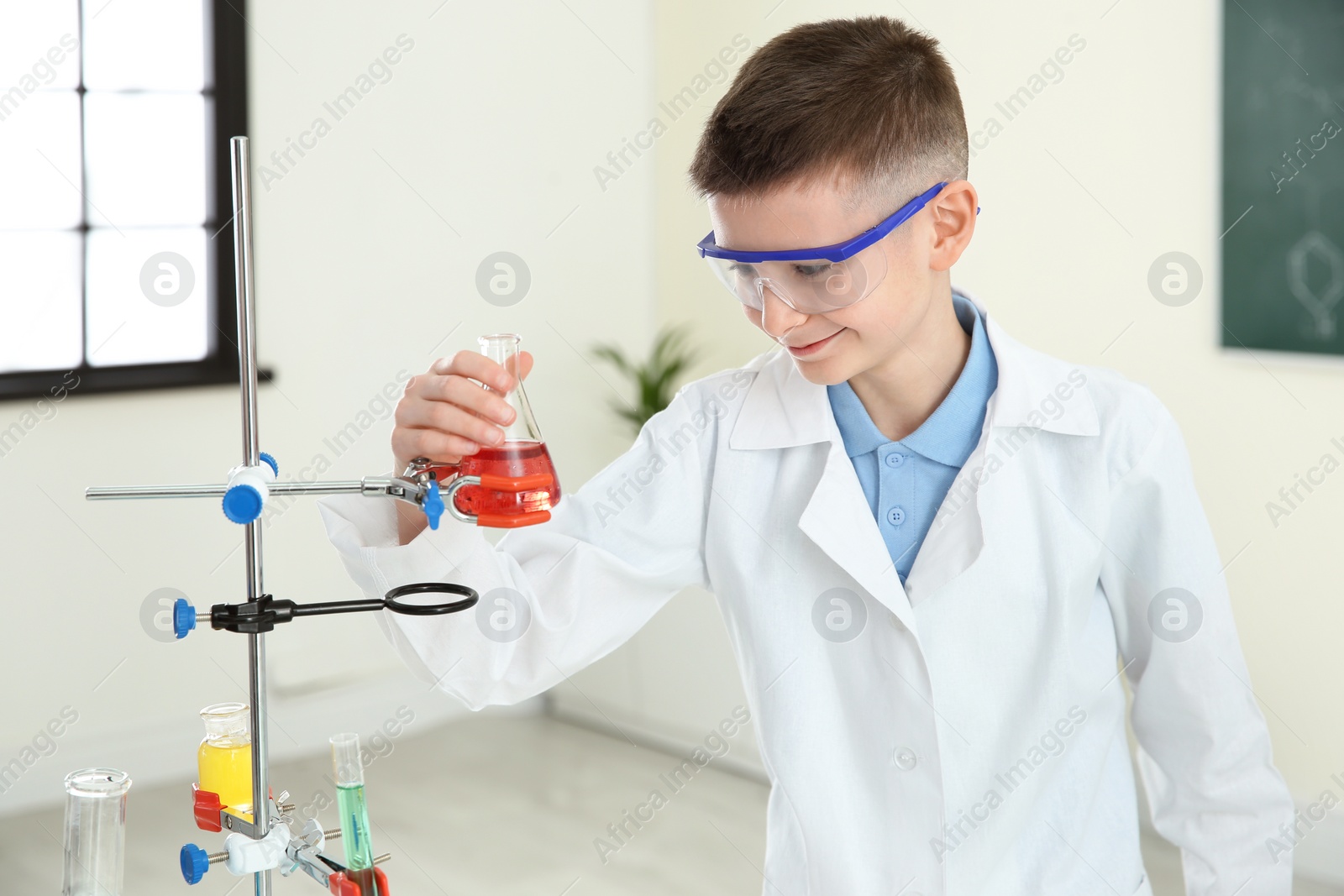 Photo of Smiling pupil looking at flask with reagent in chemistry class