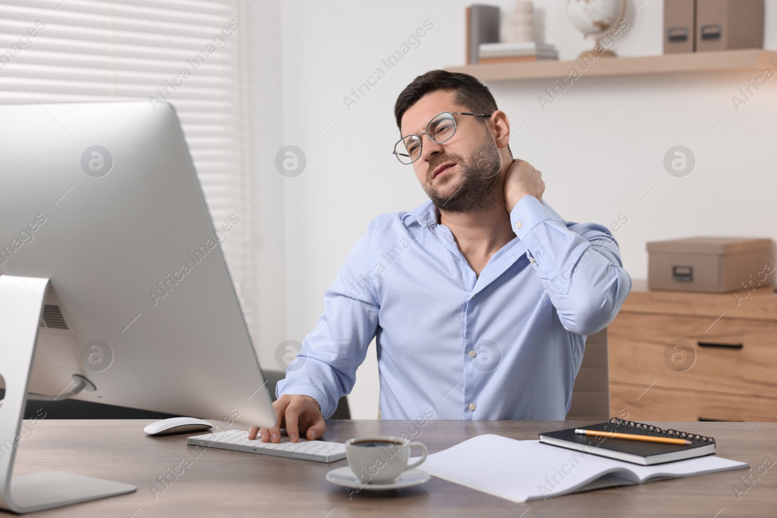 Photo of Man suffering from neck pain in office