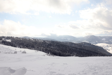 Picturesque mountain landscape with snowy hills under cloudy sky