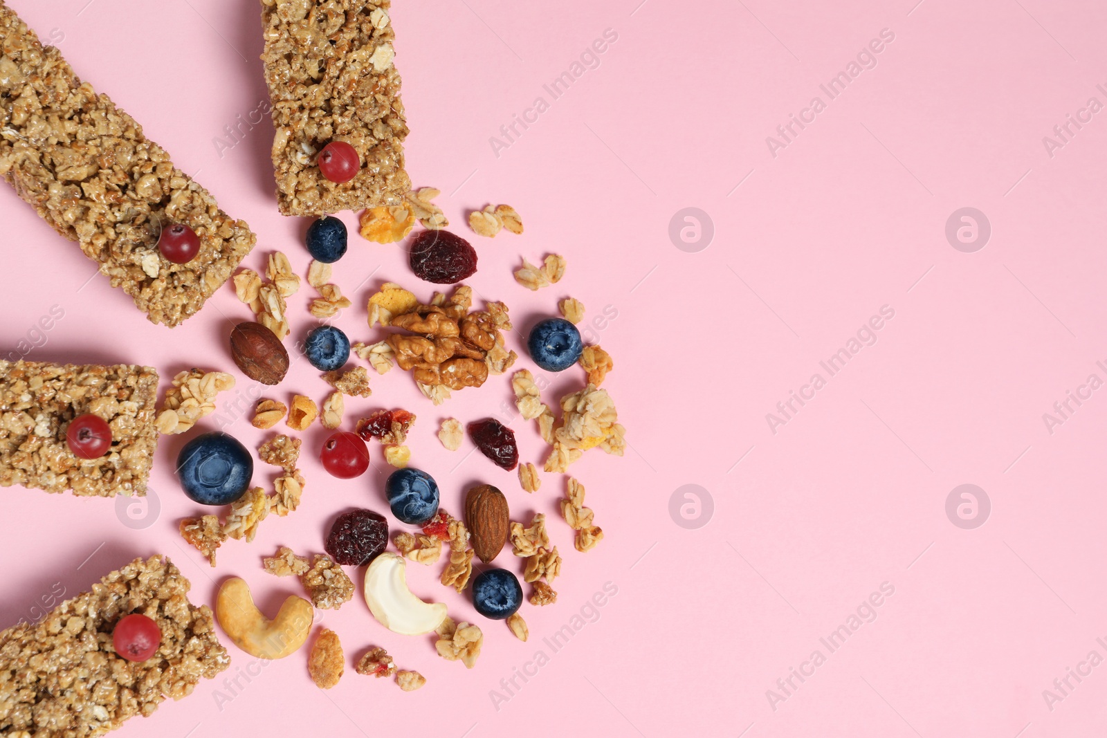 Photo of Tasty granola bars and ingredients on pink background, flat lay. Space for text