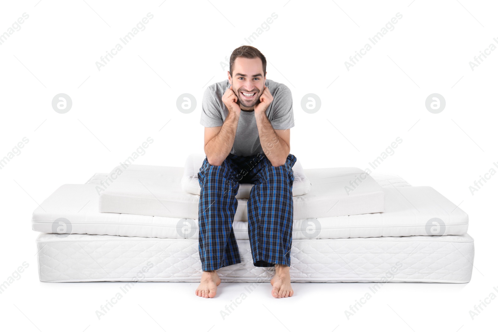 Photo of Young man sitting on mattress pile against white background