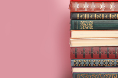 Stack of hardcover books on pink background. Space for text