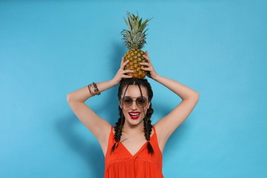 Young woman with fresh pineapple on light blue background. Exotic fruit