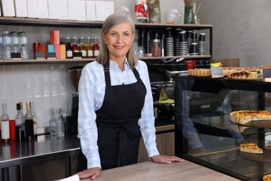 Photo of Portrait of happy business owner at cashier desk in her cafe