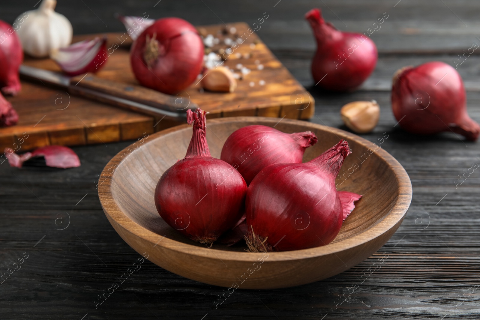 Photo of Plate with ripe red onions on wooden table