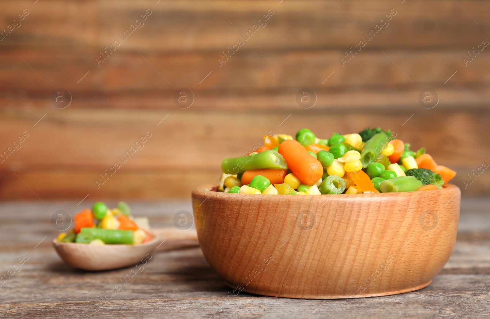 Photo of Bowl with mix of frozen vegetables on wooden table