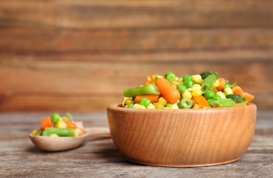 Bowl with mix of frozen vegetables on wooden table