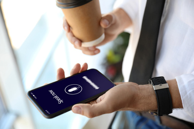 Man using voice search on smartphone indoors, closeup