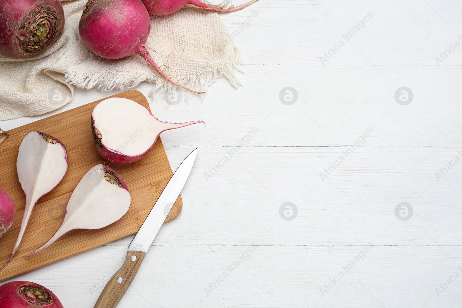 Photo of Cut and whole red turnips on white wooden table, flat lay. Space for text