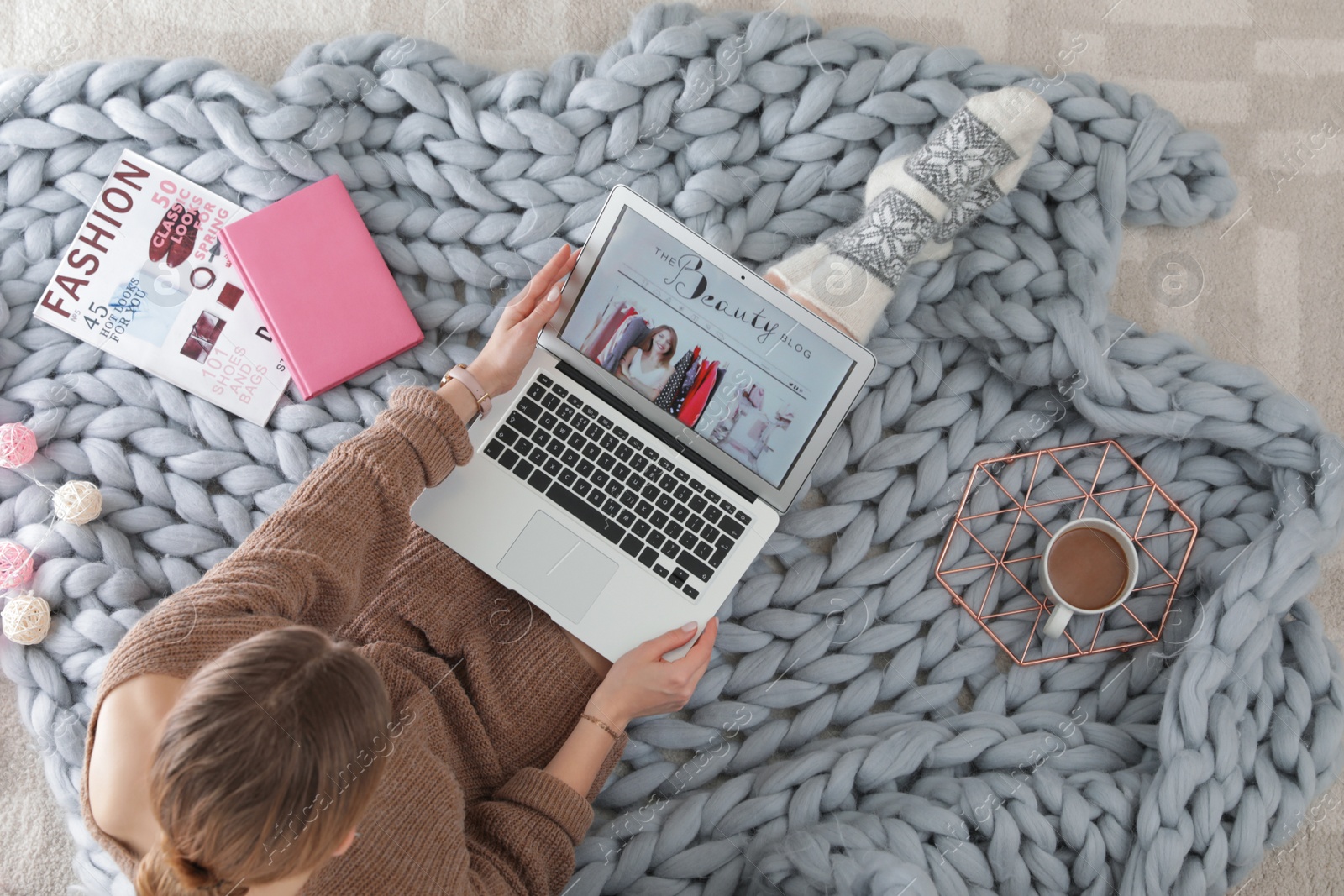 Photo of Woman holding laptop with open beauty blogger site on floor, top view