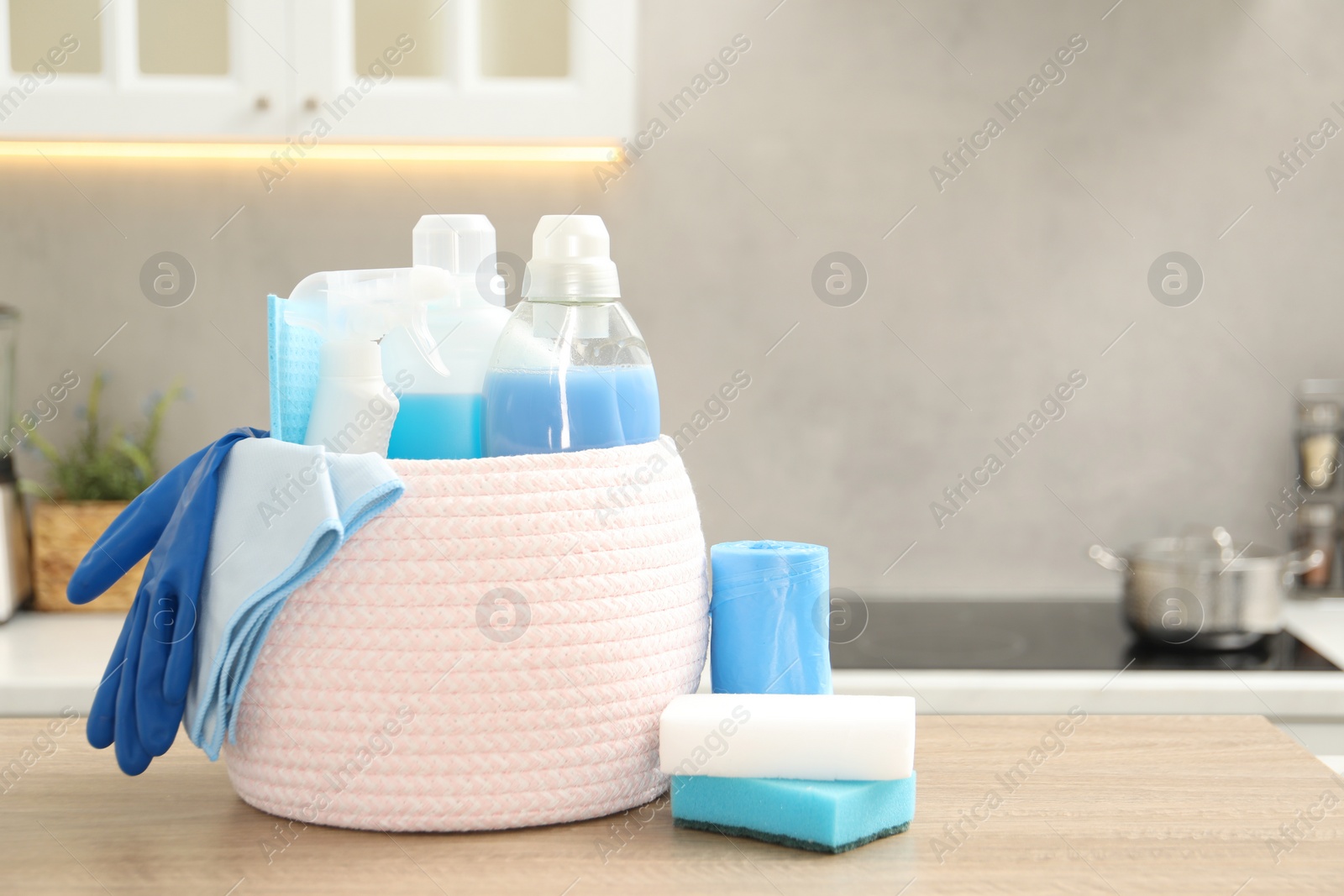 Photo of Different cleaning supplies in basket on table. Space for text