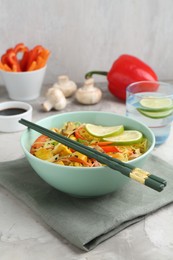 Photo of Stir-fry. Delicious cooked noodles with chicken and vegetables in bowl served on gray textured table